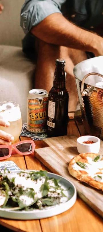 A patio table with food and a bucket of drinks