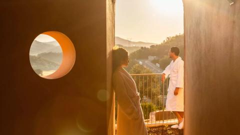 two people stand in white robes on balcony