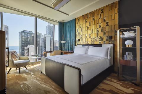 A room with floor to ceiling windows, a queen bed, and desk at Viceroy Chicago