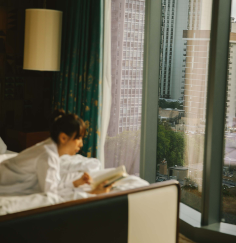 A woman laying on a bed reading a book at Viceroy Chicago