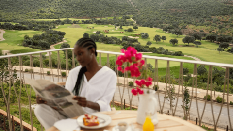 A woman reading the paper of a balcony at Ombria Algarve