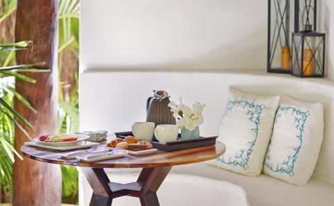 A small round table with coffee and breakfast food items at Viceroy Riviera Maya