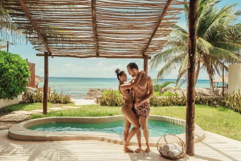 A couple in swimwear holding each other by their private pool at Viceroy Riviera Maya