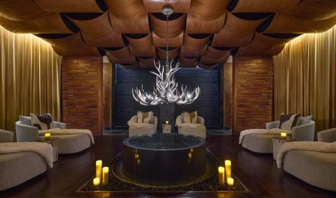 A dime lit spa room with large round loungers and candles lit along the floor at Viceroy Snowmass