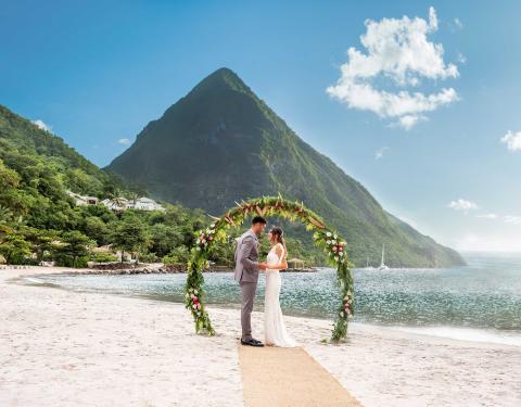 A couple getting married on the beach at Sugar Beach with themountains behind them