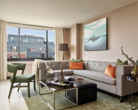 A room at Viceroy Washington DC with an L-shape couch, coffee table, chair, and balcony