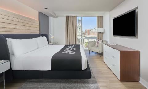 A king bed, dresser, TV, chair, and balcony in a room at Viceroy Zena Washington DC
