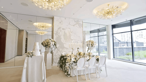 A room with a table with 3 chairs setup with wedding decorations and a table off to the left side with a wedding cake on it at a venue at Viceroy Chicago