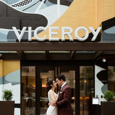 couple stand in front of colourful hotel with Viceroy sign