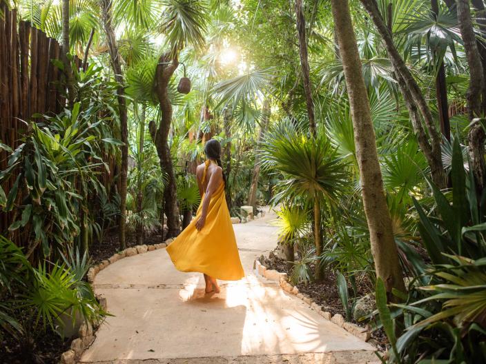 woman in yellow dress walks through jungle