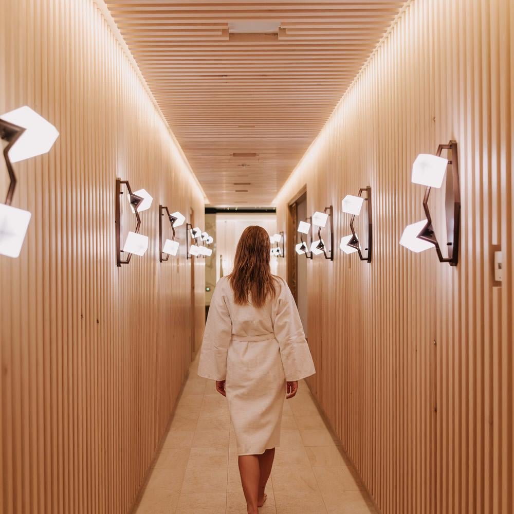 A woman in a bath robe walks along a wood-panelled corridor at the Viceroy Kopaonik Serbia spa