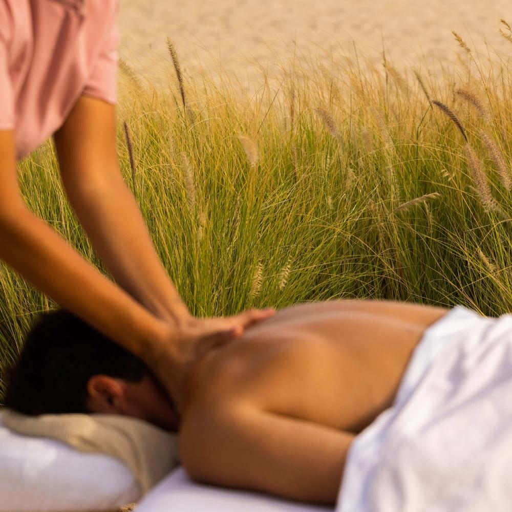 A man receives a massage outdoors next to the beach in Los Cabos