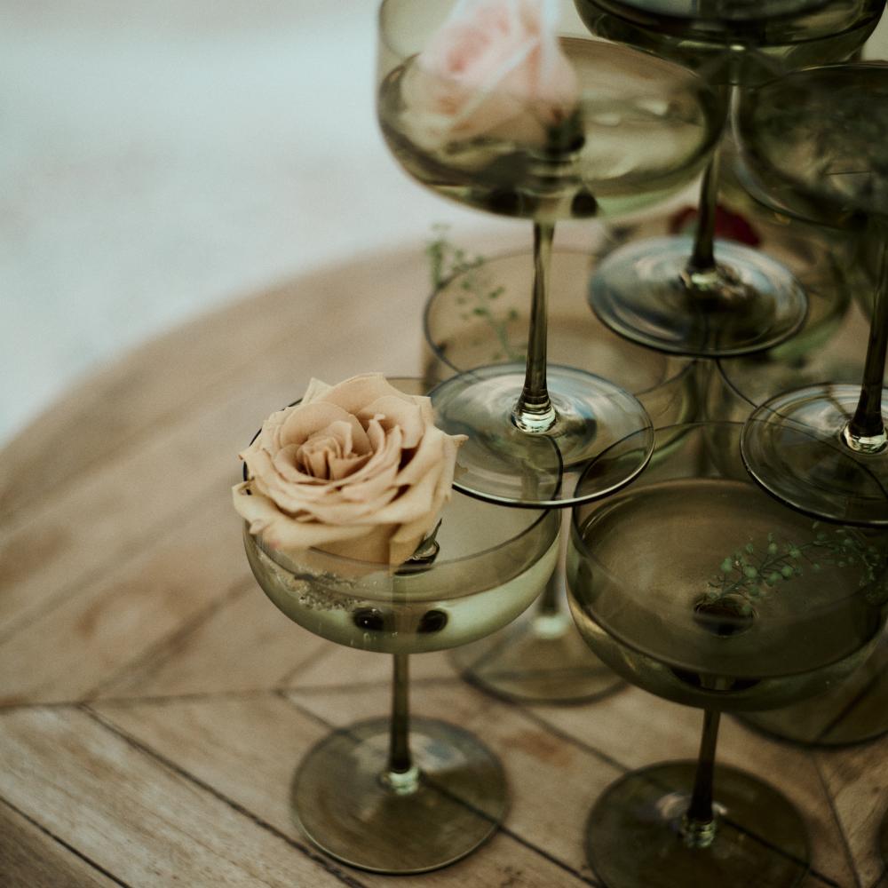 A beautiful arrangement of wine glasses with roses in them