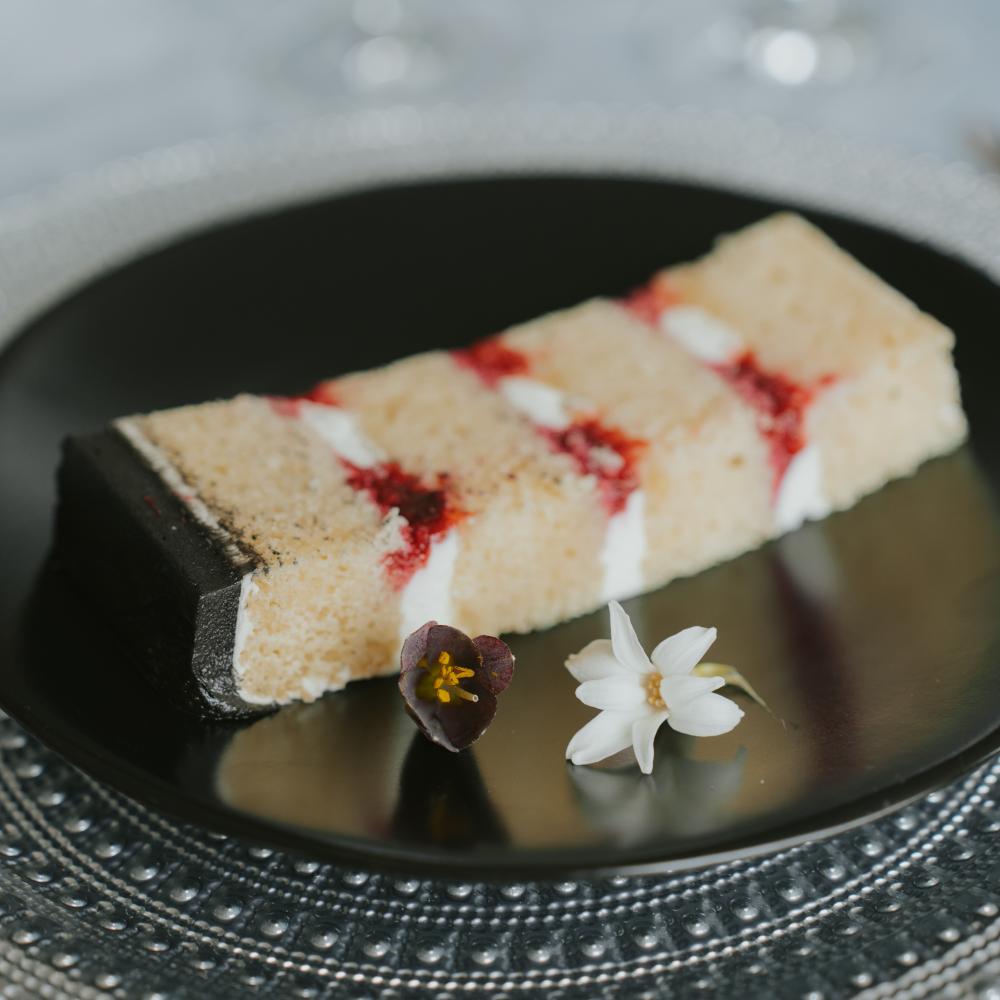 A beautiful cake piece on a black plate 