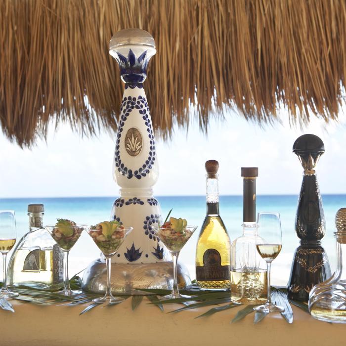 bottles of varied tequila sit on table in front of ocean