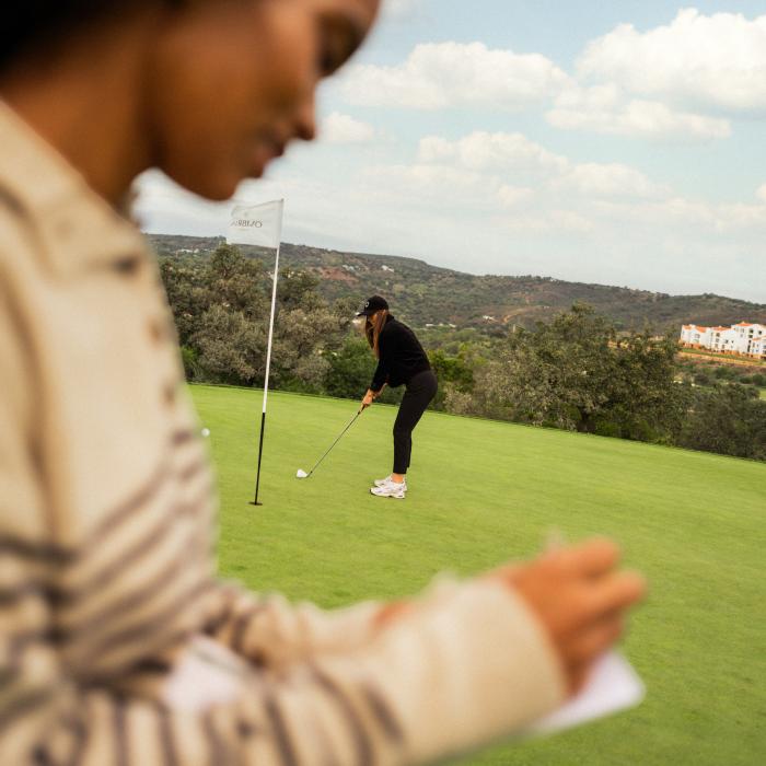 A woman putting and a woman taking score will golfing at Viceroy Ombria Algarve