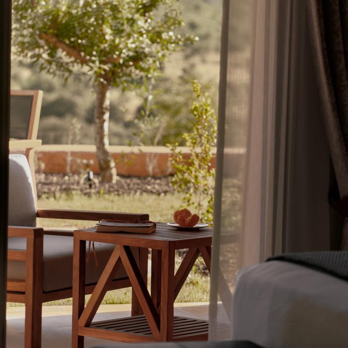 An outdoor terrace with patio furniture, looking out on the lush green Algarve countryside through a patio doorway