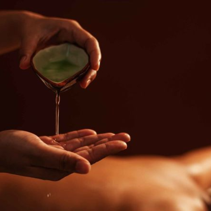 A masseuse pours oil on their hands.