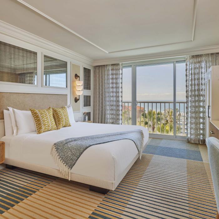 A spacious guestroom at Viceroy Santa Monica, with a queen bed and a balcony looking out on the ocean