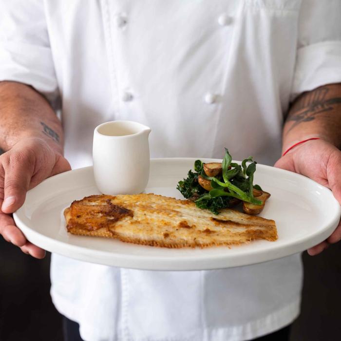 A chef holding a panfried fish dish at Saltwood Restaurant