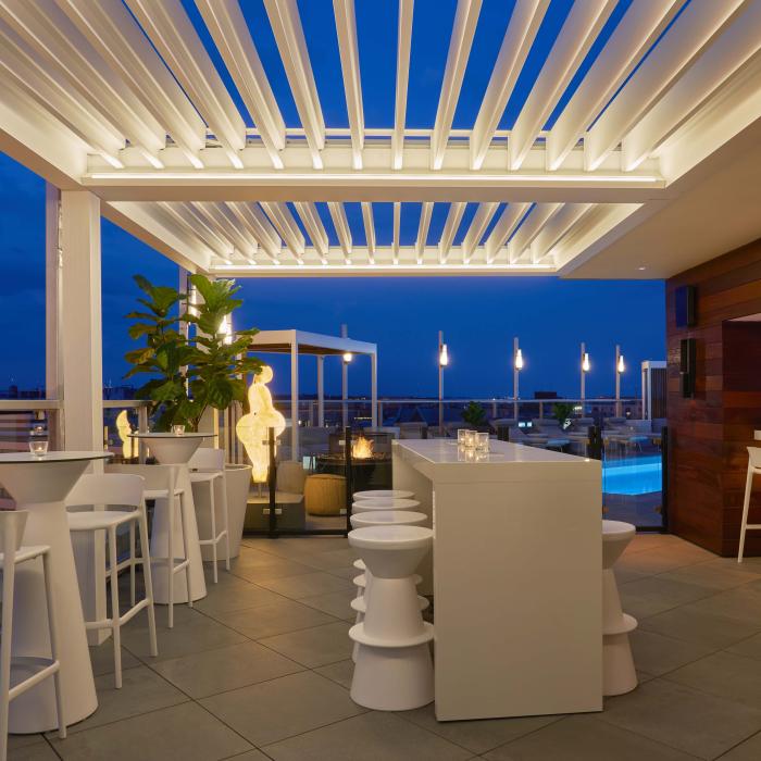 O Hedy's Rooftop, um terraço elegante com aquecedores e um toldo de treliça branca, à noite