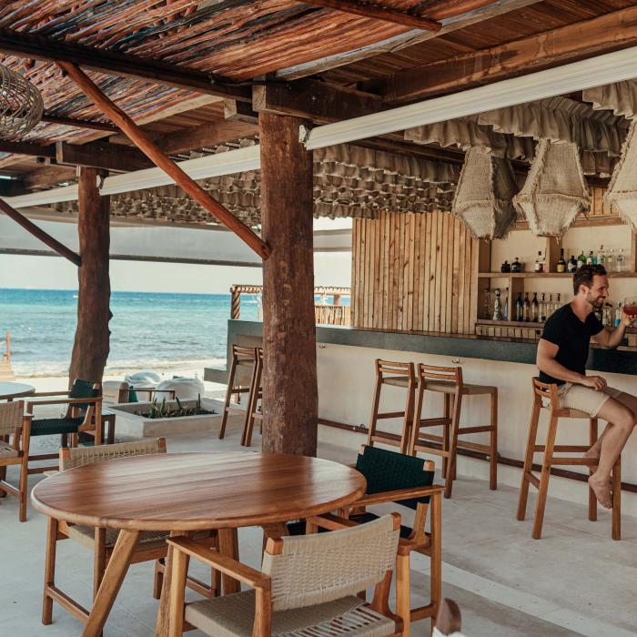 Coral Grill + Bar at Viceroy Riviera Maya, with two patrons having a drink at the bar in view of the ocean