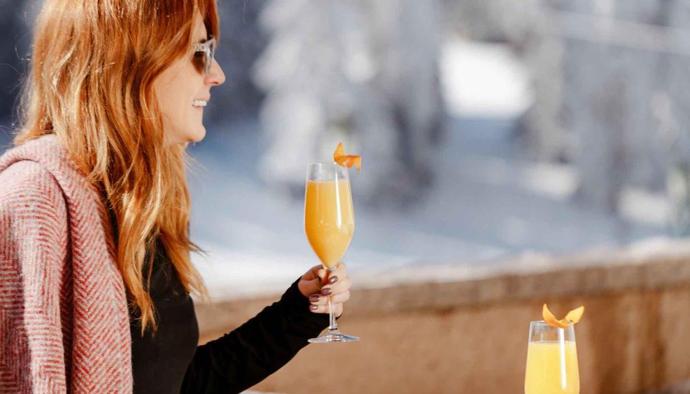 woman holding a mimosa sits outside with winter background