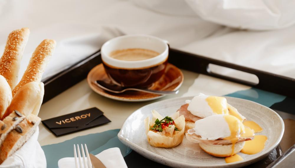 Uma bandeja de pequeno-almoço na cama, com uma sanduíche de ovo e um café