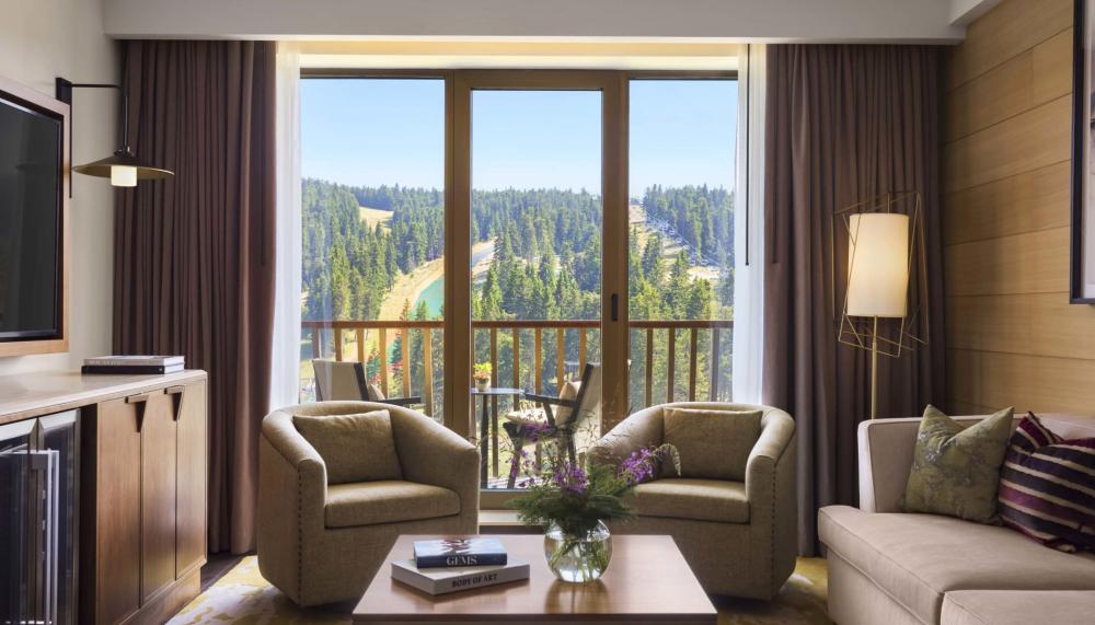 Le coin salon, équipé d'une télévision, d'un canapé et de deux fauteuils, dans une suite du Viceroy Kopaonik Serbia