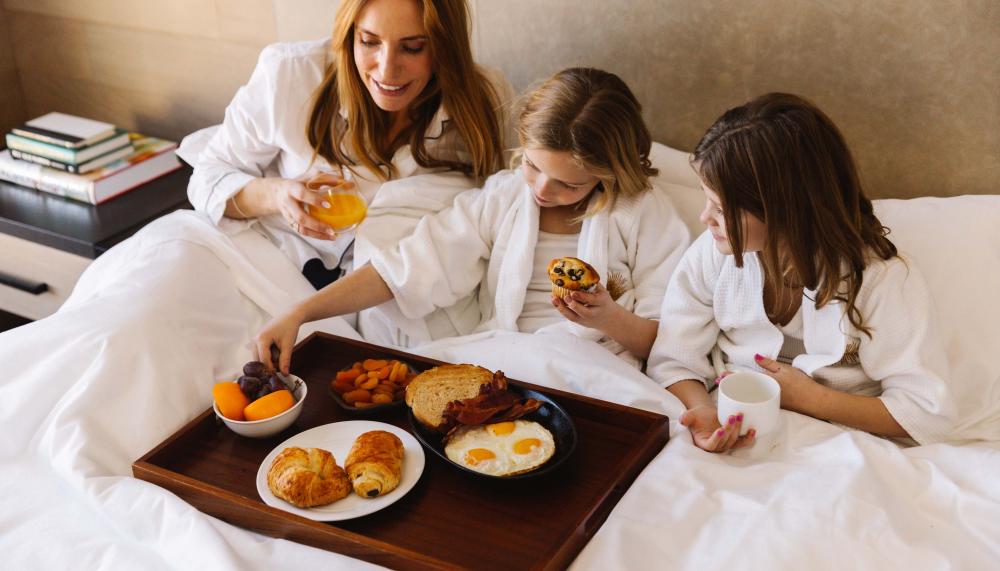 A mother and her two kids having breakfast in bed at Viceroy Snowmass