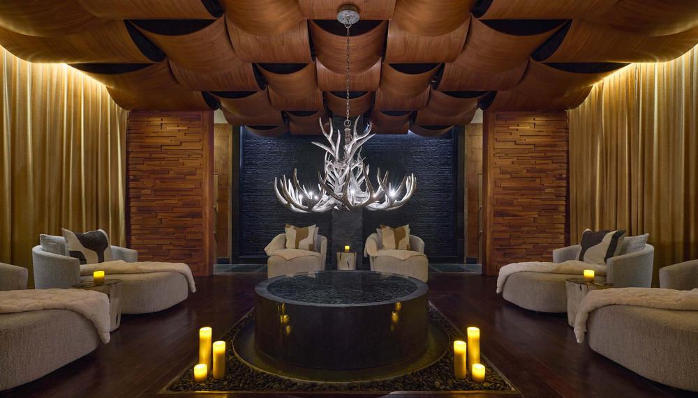 A dime lit spa room with large round loungers and candles lit along the floor at Viceroy Snowmass