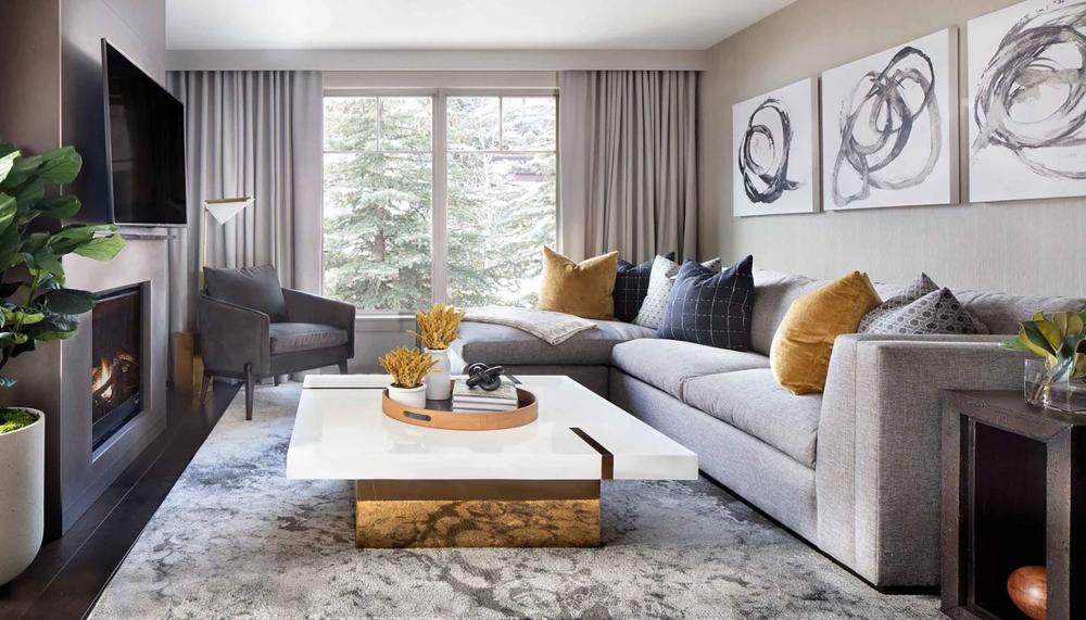 The large living area with a white marble coffee table, couch, and a television at Viceroy Snowmass