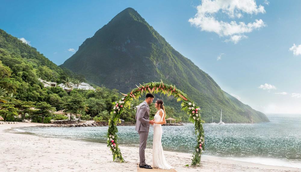 A couple getting married on the beach at Sugar Beach with themountains behind them