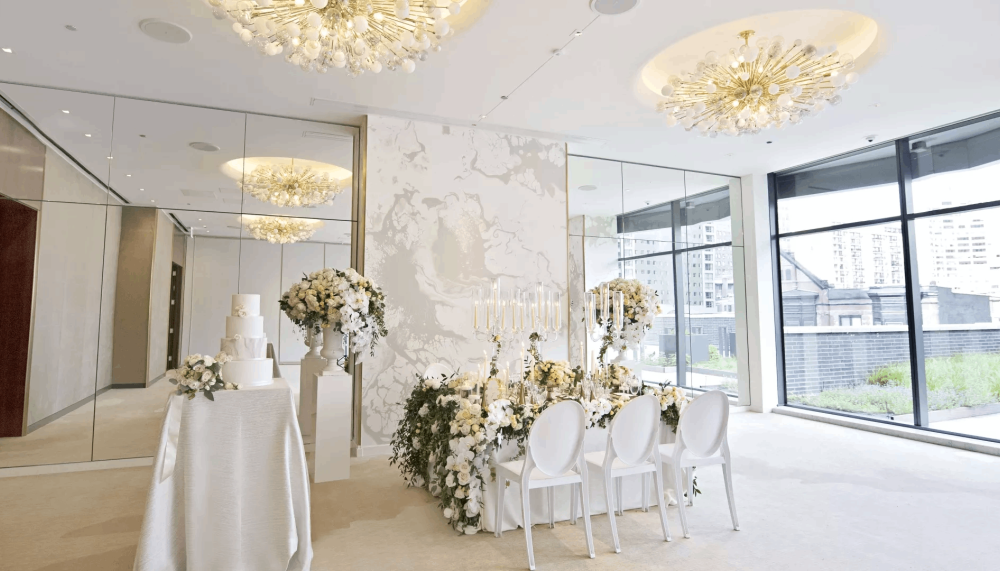 A room with a table with 3 chairs setup with wedding decorations and a table off to the left side with a wedding cake on it at a venue at Viceroy Chicago