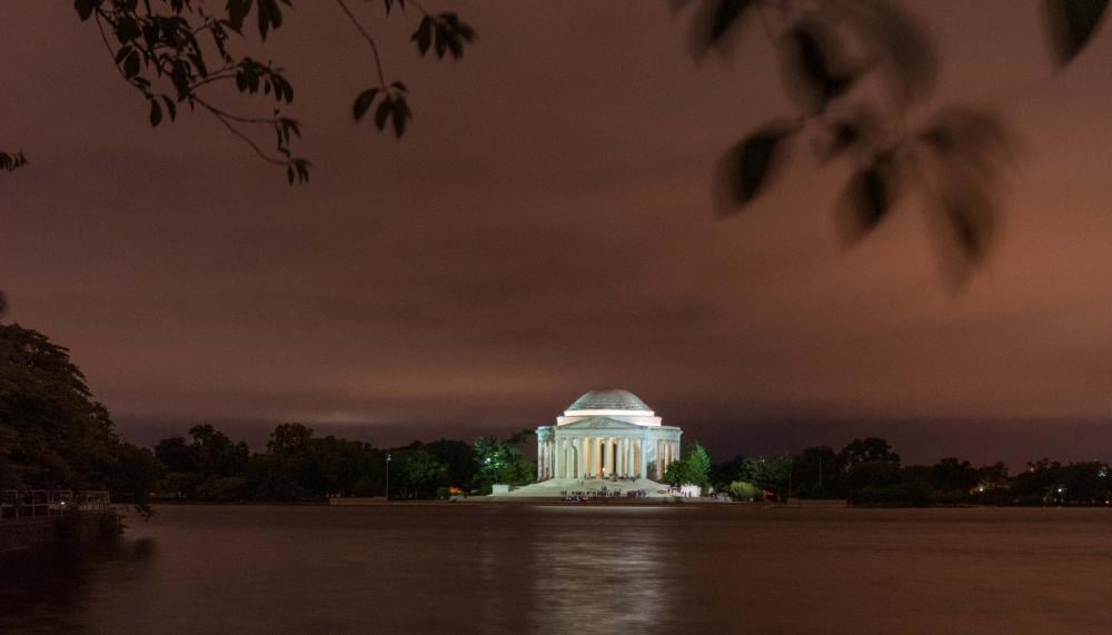 washington monument lit up at night from across a body of water