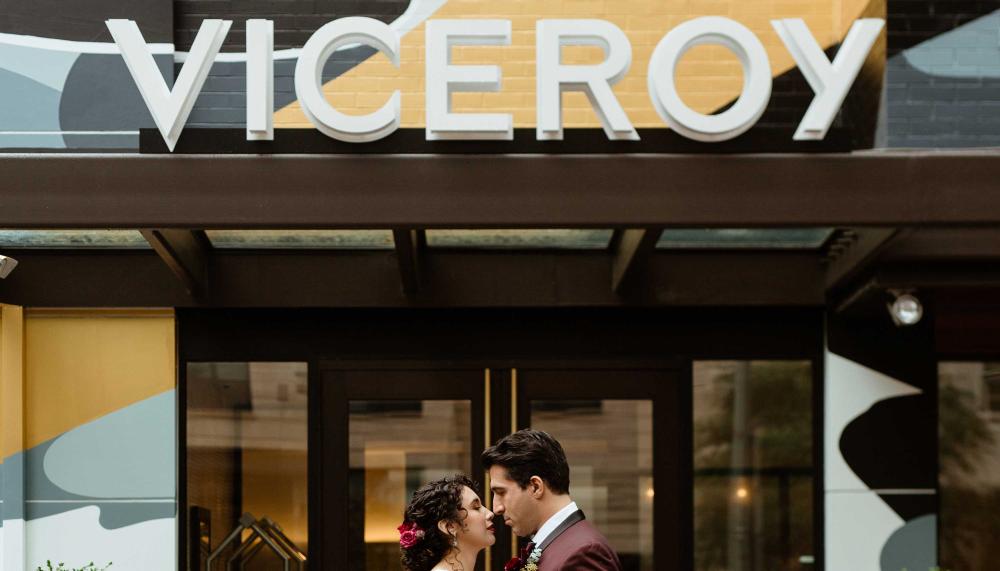 couple stand in front of colourful hotel with Viceroy sign