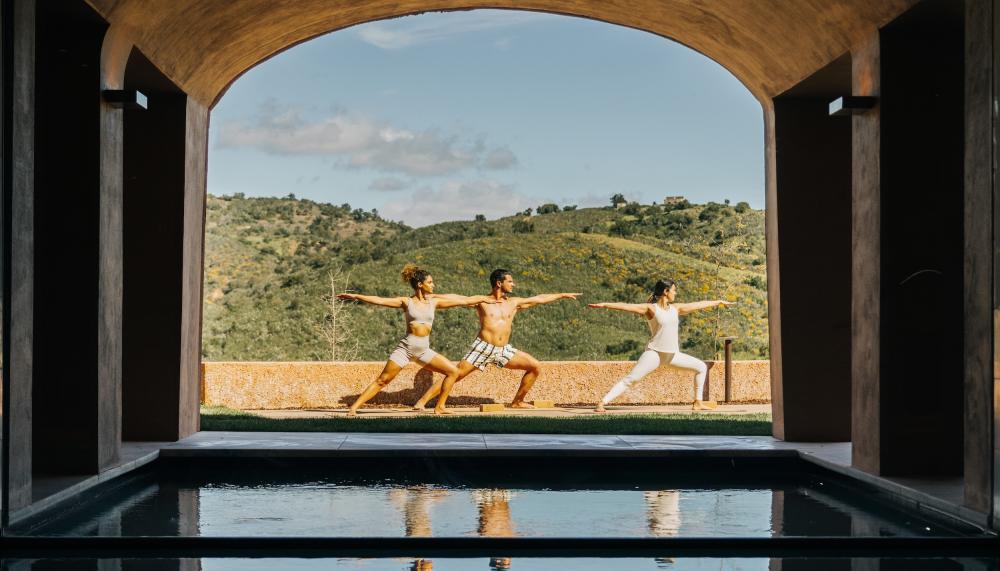 group of people doing yoga pose in background with water in foreground