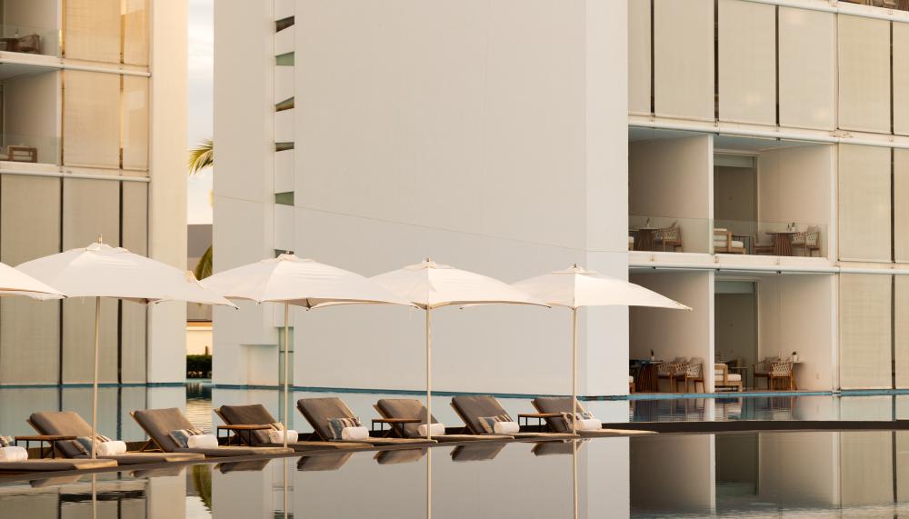 A mirror-like pool with the hotel and lounge chairs in the background.