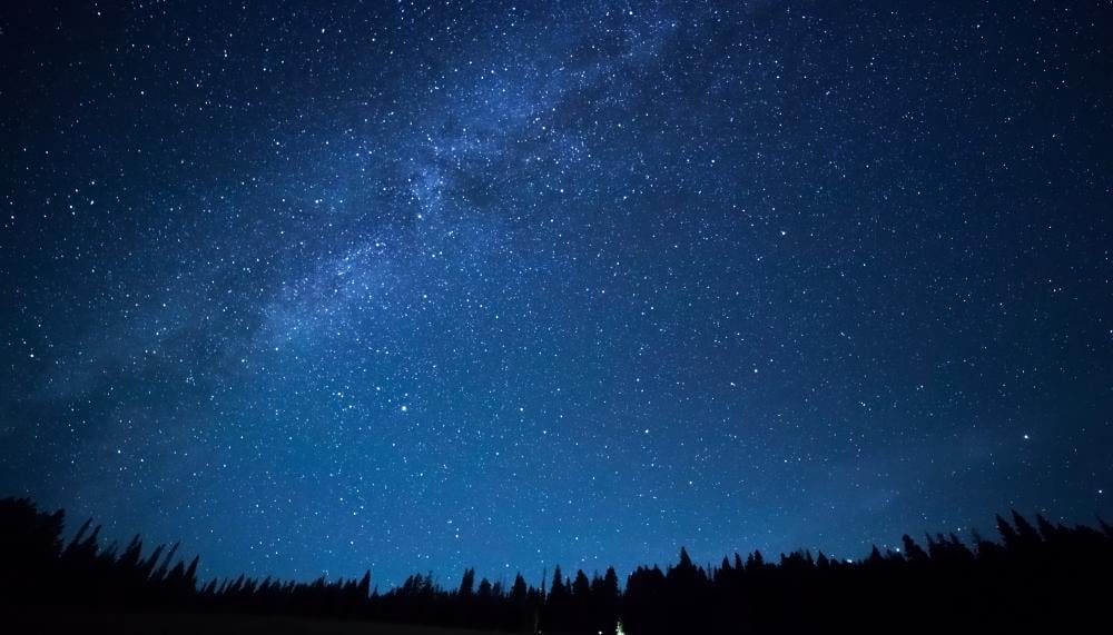 Um céu noturno com estrelas e uma galáxia