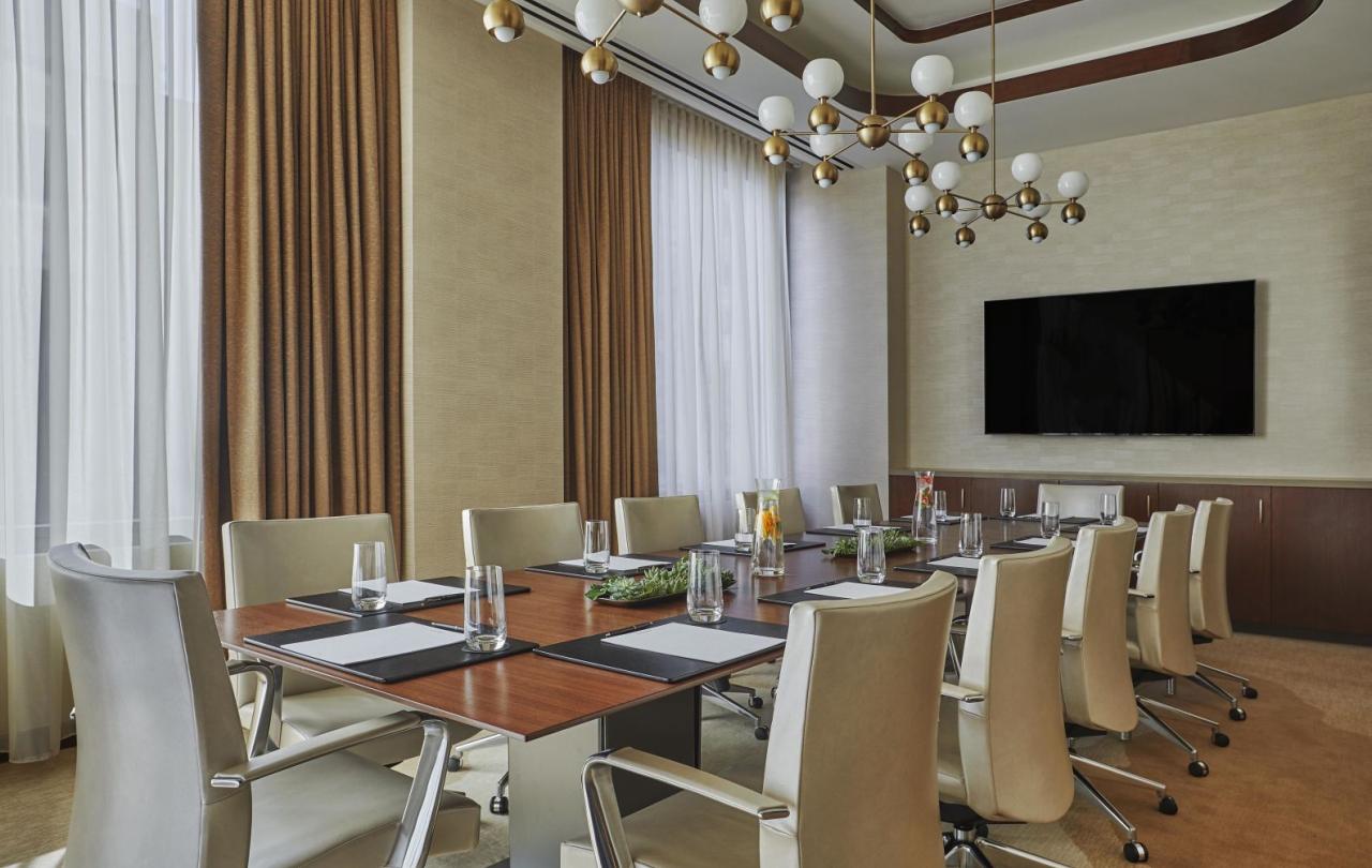 A boardroom at Viceroy Chicago, with a long table surrounded by high-back chairs and a wall mounted television