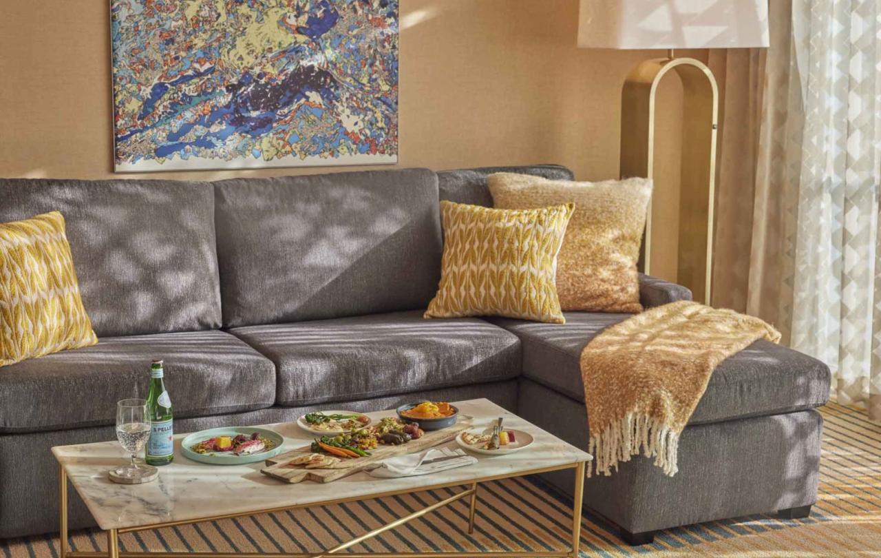Gray couch with orange yellow throw pillows and blanket