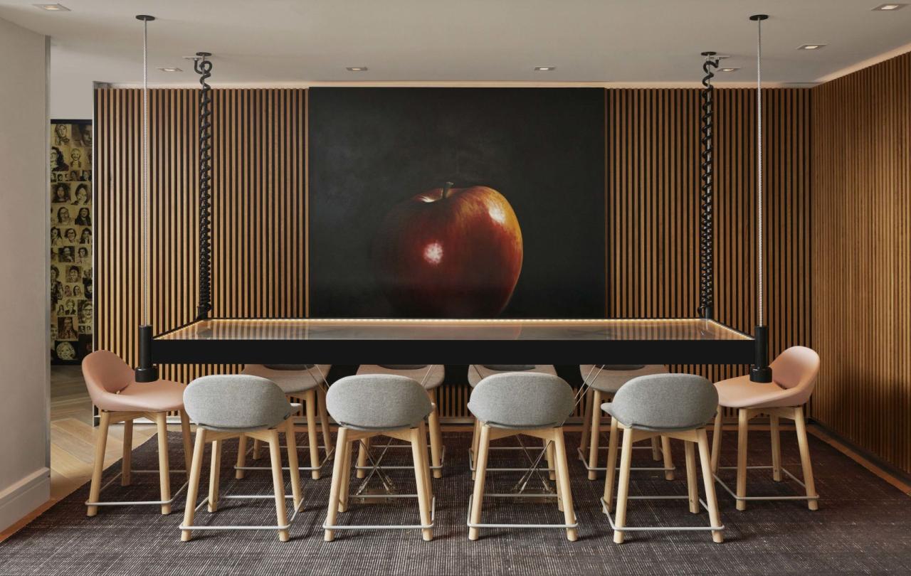 A table with 6 chairs and a large apple painting on the wall at Viceroy Zena