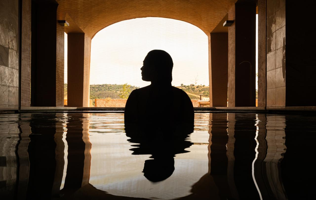 Perfil da silhueta de uma pessoa submersa numa piscina tranquila, com reflexos nítidos.