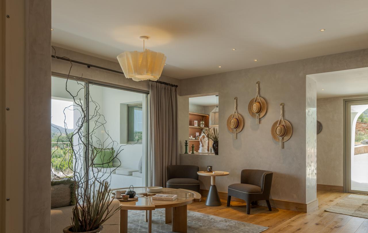 Um acolhedor salão de spa com poltronas confortáveis, chapéus de palha trançados como decoração nas paredes e grandes portas de vidro que dão para o pátio.