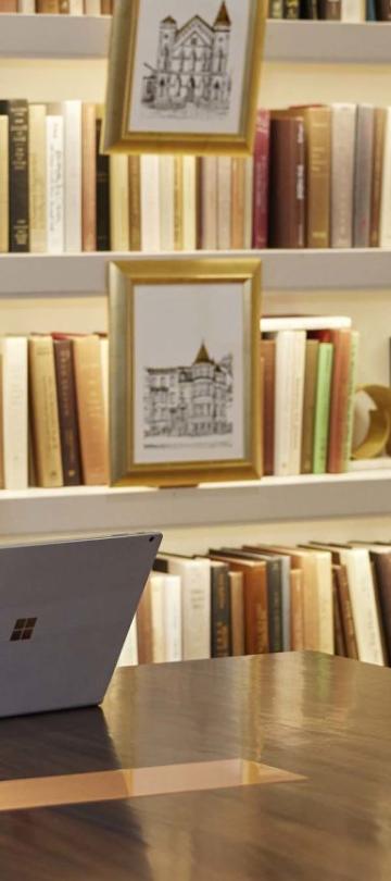 A Person Sitting At A Table With A Book Shelf