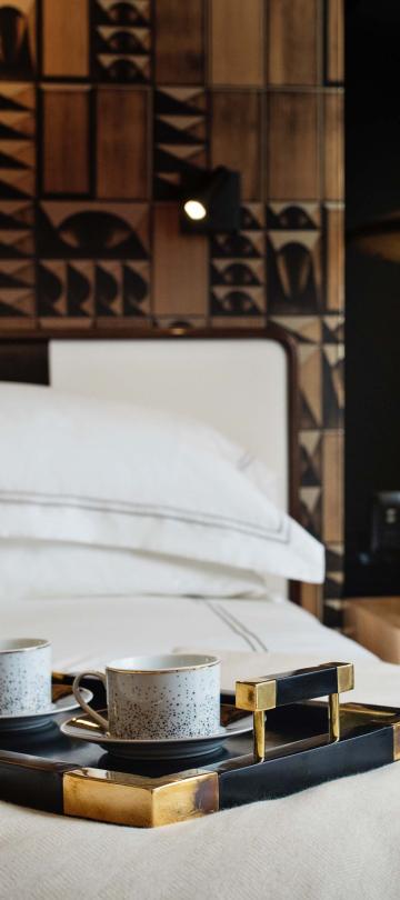tray with two cups of coffee sit on a bed