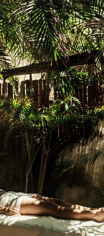 woman lays on treatment table in jungle