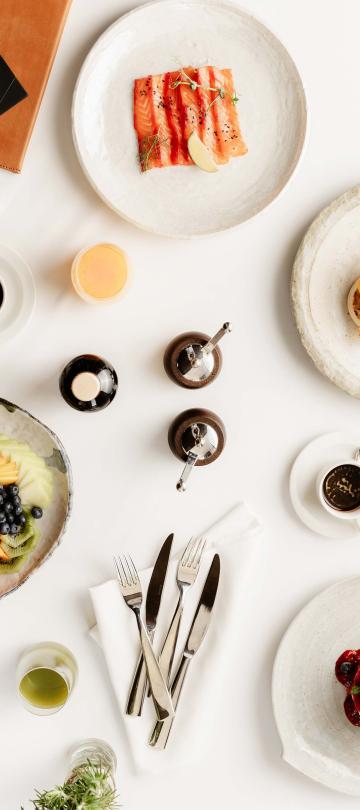 view from above of plates of brunch dishes on white table 