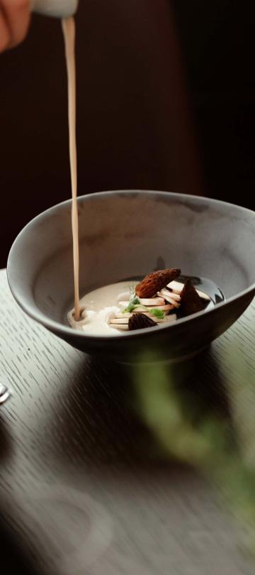person pours white sauce into a bowl 