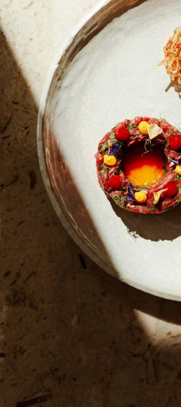 white plate with tartare under shadow from window